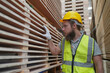 © FotoArtist - Warehouse worker working at lumber yard in Large Warehouse. Worker are  Inventory check at Storage shelves in lumberyard.