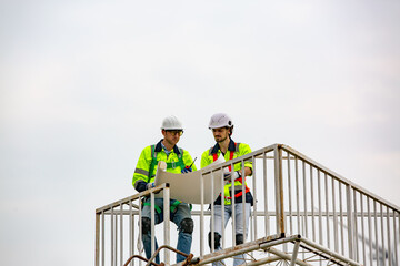 Engineer in protective workwear and windturbines on the background. Concept of alternative energy and its maintenance