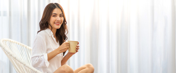 portrait of smiling happy cheerful beauty pretty asian woman relaxing drinking and looking at cup of