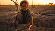 Black boy Hungry starving poor little child looking at the camera, amidst drought cracked ground dead big tree
