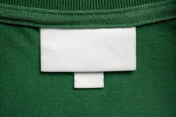 Wall Mural - Blank white laundry care clothes label on green shirt fabric texture background