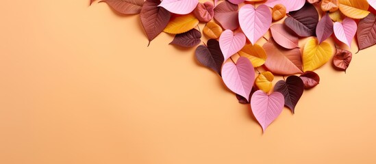 Wall Mural - Pink studio shoot with heart shaped cutout surrounded by autumn leaves in orange green yellow and brown Top down view and horizontal layout with empty space