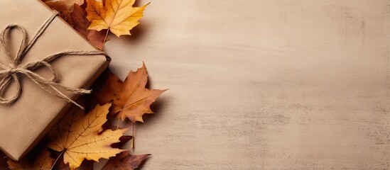 Poster - Autumn arrangement featuring dried leaves a wrapped gift placed in a corner on rustic linen background Top view copy space