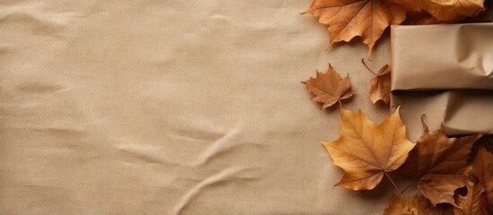 Aufkleber - Autumn arrangement featuring dried leaves a wrapped gift placed in a corner on rustic linen background Top view copy space