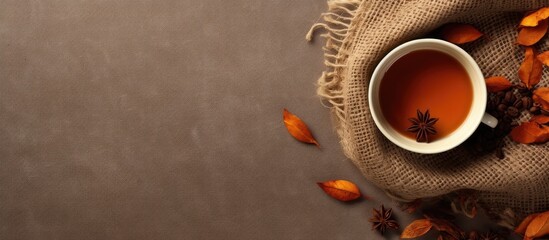 Poster - Flat lay composition in autumn or winter with a coffee cup dry leaves and dried orange on a linen fabric background Copy space available representing autumn or fall