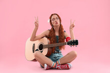Stylish Young Hippie Woman With Guitar Showing V-sign On Pink Background