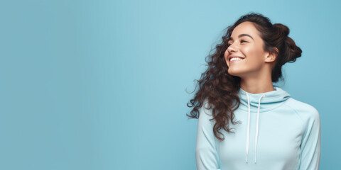 Portrait of young smiling fitness woman on blue background with copy space