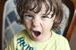 Closeup headshot portrait of a young white Caucasian boy throwing a temper tantrum, looking directly at the camera with an angry expression on his face