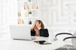 Hysterical business woman hiding behind desktop and looking at laptop in the office. Business crisis and bankruptcy concept