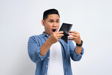 No money. Shocked young Asian man in casual shirt looking at empty wallet, having financial problems isolated on white background