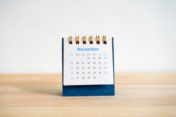 Wall Mural - An November 2023 calendar desk for the organizer to plan and reminder isolated on wood table and white background, minimal style. Front view of blue small table calendar with page of the 11th month.