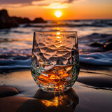 Fondo con detalle y textura de vaso de cristal tallado sobre arena de playa, con mar y puesta de sol