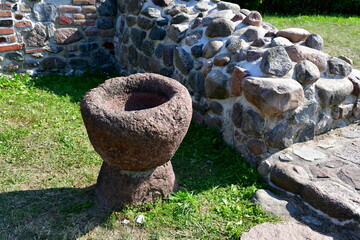 A close up on a wooden bowl or chalice being a remnant of a medieval chapel seen next to ruins of the walls made out of rock, stone, or boulder set connected with some plaster seen on a sunny day