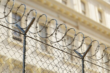 A Jail Or Embassy Building Surrounded By A Tall Metal Fence With Barbed Wire