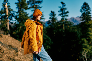 Canvas Print - Woman red hair on a hike in the mountains walking and looking at the view of nature autumn in a yellow cape and hat full-length happiness