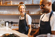 © (JLco) Julia Amaral - Two baristas standing behind the counter, preparing to serve coffee