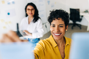 Wall Mural - Creative business women writing ideas on sticky notes in an office