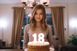Cute 18 year old teen girl in front of a cake, celebrating her eighteen adulthood birthday , majority or legal age concept