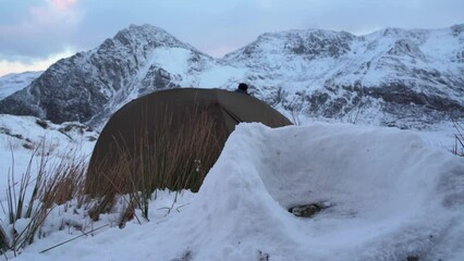 Canvas Print - Winter camping scene with snow structure, wild camping tent and a man in the mountains