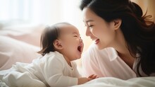 New Asian Mom Playing With Cute Newborn Baby On Bed Smiling And Happy And Baby