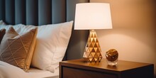 Stylish Golden Lamp And Stationery On A Wooden Bedside Table In The Bedroom.