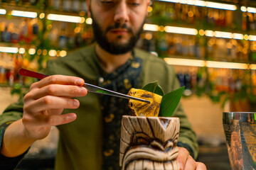 a bartender in a bar or restaurant decorates a freshly prepared alcoholic cocktail lays out the decor with tongs