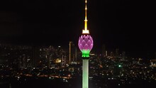 Orbit Shot Around Top Of Tall TV Tower In Lotus Flower Design. Colombo Lotus Tower Colourfully Glowing Into Night City. Colombo, Sri Lanka