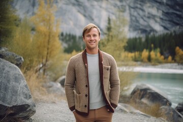 Wall Mural - Environmental portrait photography of a grinning boy in his 30s wearing a chic cardigan at the banff national park in alberta canada. With generative AI technology