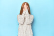 Redhead young woman on blue background holding hands in pray near mouth, feels confident.