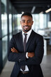 © Adriana - Smiling black executive posing with his arms crossed at the office looking at the camera