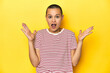 © Asier - Shaved head woman in red striped tee, yellow backdrop celebrating a victory or success, he is surprised and shocked.