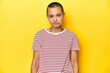 © Asier - Shaved head woman in red striped tee, yellow backdrop sad, serious face, feeling miserable and displeased.