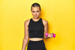 © Asier - Shaved-head sportswoman lifting weights, yellow studio backdrop