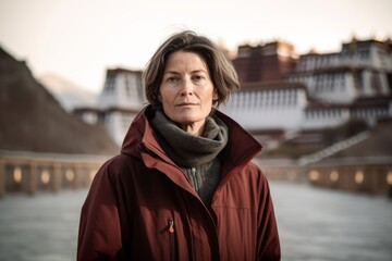 Wall Mural - Photography in the style of pensive portraiture of a tender mature woman wearing a lightweight packable anorak at the potala palace in lhasa tibet. With generative AI technology