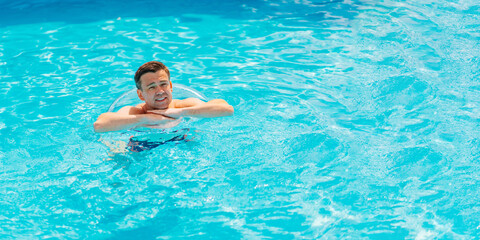 Wall Mural - Portrait of a cheerful middle-aged man in the pool with inflatable lifebuoy.