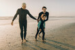 © Marko Geber - Multigenerational family of male surfers getting ready to surf on a sandy beach