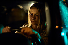 A Young Caucasian Woman, Bearing The Painful Signs Of Domestic Abuse With Visible Bruises And Blackened Eyes, Drives Her Car At Night