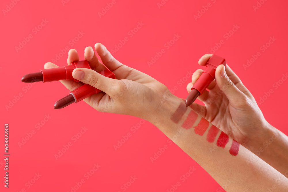 Woman with lipsticks and samples on red background