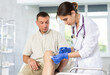 © JackF - Young female doctor performs intra-articular injection treatment of knee bursitis to middle-aged man patient