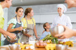 © JackF - Friendly enthusiastic tween girl learning how to cook and listening to advices of professional chef during group cooking masterclass ..