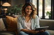 © Athena  - a young woman sits on the sofa holding a tablet, the woman smiles while looking at the tablet.
