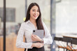 © David - Portrait of young asian woman, company worker in documents smiling and holding digital tablet, standing over office background