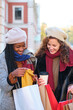 © Ladanifer - Two multiracial female friends looking the clothes they bought after shopping in winter.