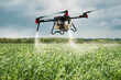 Modern technologies in agriculture. industrial drone flies over a green field and sprays useful pesticides to increase productivity and destroys harmful insects. increase productivity
