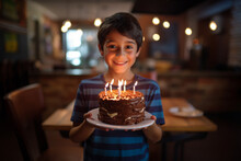 A Young Boy Holding A Chocolate Birthday Cake With Lit Candles, Birthday Celebration, Generative AI