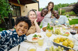 © AnnaStills - Cute African American boy in Hawaiian shirt taking selfie with his parents and grandparents while sitting by served table during family dinner