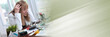 Overworked businesswoman sitting at a messy desk; panoramic banner
