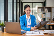 © bongkarn - A professional Asian businesswoman or female banker is examining business documents at her desk.