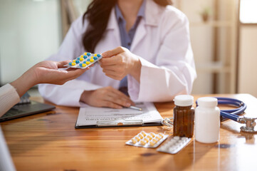 Wall Mural - A professional female doctor is describing pills to a female patient during an appointment.