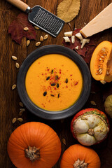 Top view of nutritious pumpkin soup in bowl with cheese on rustic wooden table